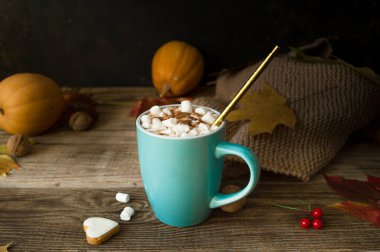 Sonbahar yaprakları ve ahşap bir masanın üzerinde balkabakları olan mavi seramik bir kupada kremalı sıcak kakao. Hygge konsepti, samimi sonbahar, Şükran Günü, sonbahar. Sıcak içecekler. Sakin bir sonbahar hayatı..