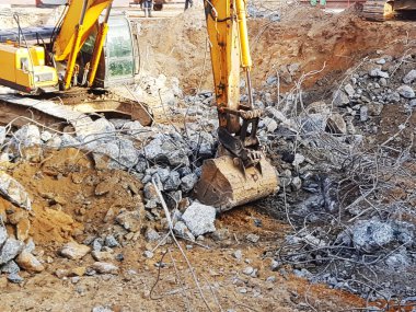 Güçlü kazıcılar betonu söker. İnşaat alanı. Endüstriyel bir binanın sökülmesi. Güçlendirilmiş betonun tahribatı.