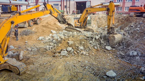 Güçlü kazıcılar betonu söker. İnşaat alanı. Endüstriyel bir binanın sökülmesi. Güçlendirilmiş betonun tahribatı.