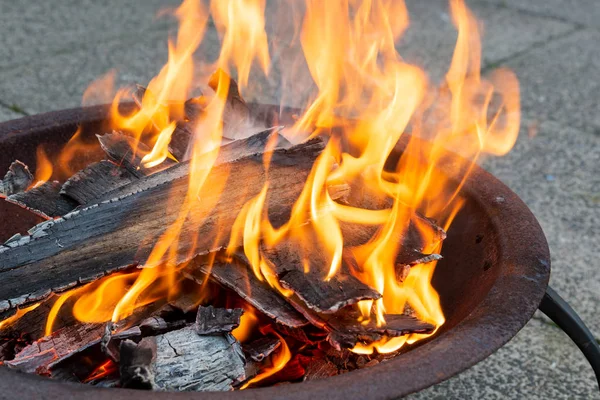 Wood burning brightly in a metal fire pit