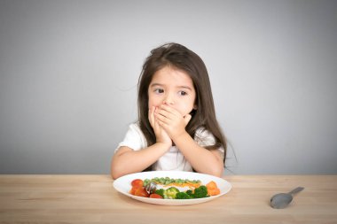 Çocuklar için beslenme ve sağlıklı beslenme alışkanlıkları kavramı. Çocuklar sebze yemeyi sevmezler. Küçük sevimli çocuk yarı yarış kız sağlıklı sebze yemek için reddediyorum.
