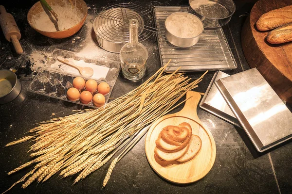 Cozinha desordenada por um iniciante de padaria caseira com ingredientes de cozimento como farinha, rolo de pino, batedor, casca de ovo malha, e moldes de plástico para assar. Empilhe a farinha em uma tigela com a gema de ovo, vista superior — Fotografia de Stock