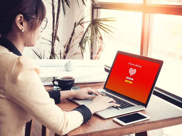 Online liefde concept: Office meisje met behulp van online dating website op een laptop display, hardhout Desktop en briefpapier op de achtergrond — Stockfoto