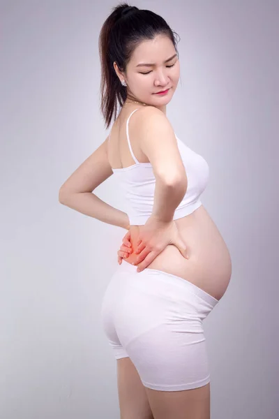 Concept de problème sain enceinte : Jeune femme enceinte asiatique avec une forte douleur massant son mal de dos - douleur en rouge — Photo