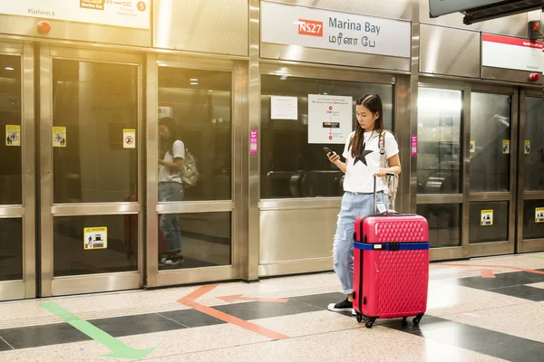 Giovane viaggiatore asiatico con applicazione uso bagagli su smartphone a Marina Bay Station, Singapore — Foto Stock