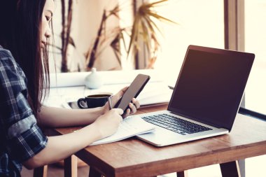 Öğrenci iş süreci kavramı. Genç Asisn kadın jenerik tasarım dizüstü bilgisayar ile üniversite projesi çalışıyor. Analiz planları eller, akıllı telefon kullanarak. 