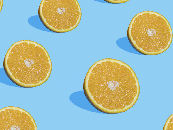 Fresh orange slices on blue background with shadow , top view, flat lay, close up , pattern. Summer and healthy citrus fruit concept