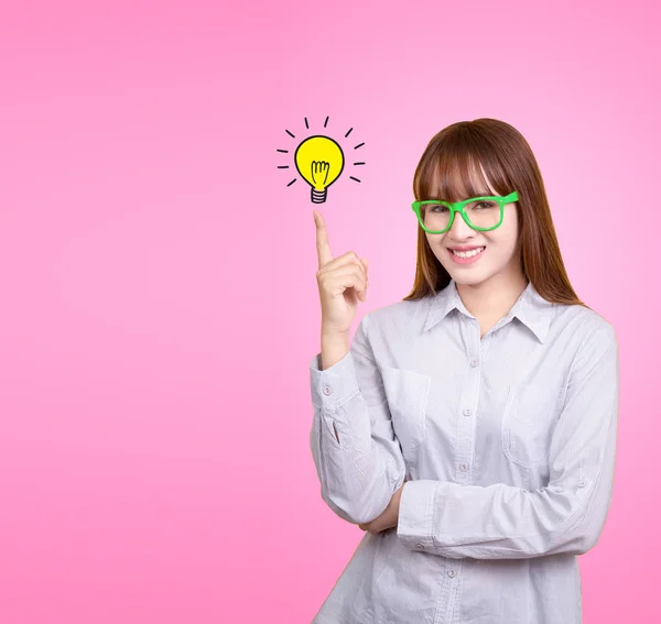 Business Asian woman with green glasses stand and have idea lamp bulb light on women fingertip pink background, for your design for poster and advertising text. Beautiful Asia female model in her 20s. — Stock Photo, Image