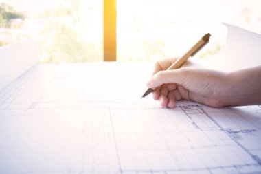 İnşaat, tasarımcı ve yenileme konsepti. : Plan üzerinde çalışan mimar, mimar işyeri. Yeni başlangıç projesi ile çalışan mimari çizilmiş kalem, ışık etkisi ile yan görünüm.
