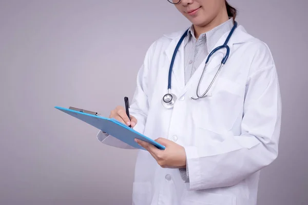 Konsep sehat: Dokter muda Asia menulis di papan klip untuk grafik pasien, wajah anonim. Cantik Asia model perempuan di usia 30-an — Stok Foto