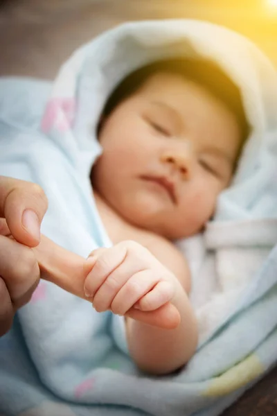 Concepto de amor y relación familiar: primer plano asiática bebé mano agarre todo el dedo de la madre con la luz de la mañana, Asia bebé retrato  . — Foto de Stock