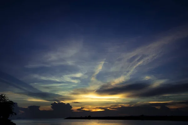 Mar durante o pôr do sol com céu nublado — Fotografia de Stock