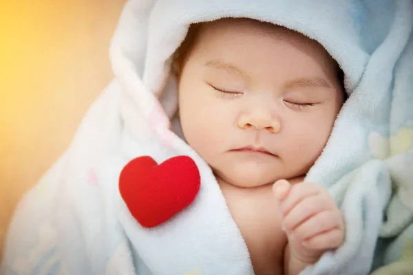 Concepto de relación de amor familiar: corazón rojo en forma de dormir lindo bebé asiático. Precioso recién nacido modelo infantil de Asia mujer en su primer año — Foto de Stock