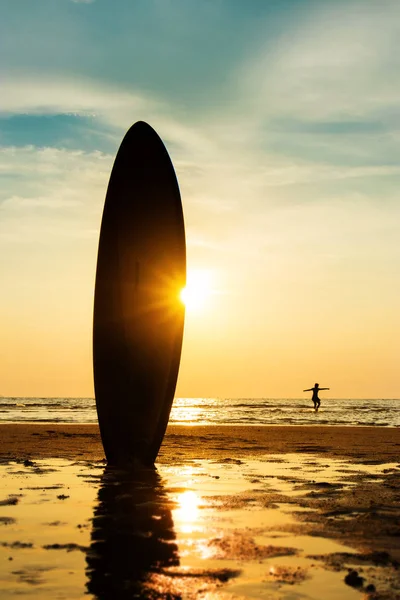 Silhueta de surfista surfando com uma prancha na praia à hora do pôr-do-sol. Bonito modelo asiático homem em seus 20 anos . — Fotografia de Stock