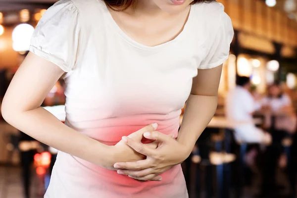 Las mujeres sufren de dolor de estómago o gastroenterólogo. Concepto con Salud y Medicina. Dolor en color rojo. Aislar con el camino de recorte en el fondo borroso restaurante — Foto de Stock