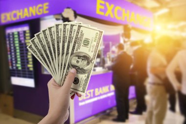 people, withdrawal, saving, finance, currency conversion and money exchange concept - hands with US dollar money with blur exchange booth background clipart