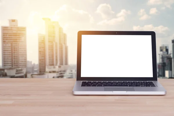 Technologie voor comfortabel business concept: blanco wit scherm op notebook, laptop met vervaging gebouw en Cityscape achtergrond, filmeffect. — Stockfoto