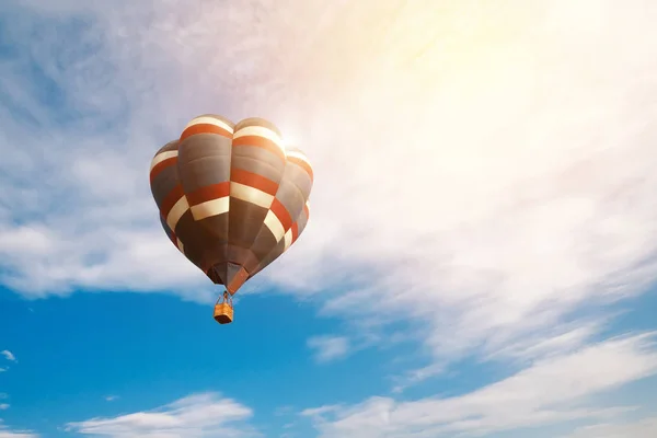 Concept de voyage et de tourisme. Ballon à air chaud coloré volant au lever du soleil avec fond bleu ciel nuageux — Photo