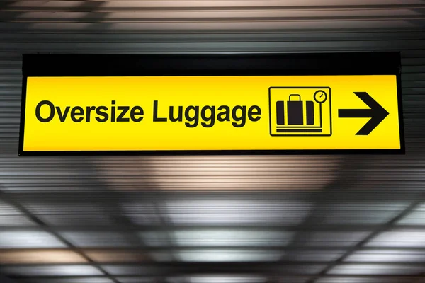 Bagagli di grandi dimensioni segno giallo con direzione freccia appendere al soffitto in aeroporto — Foto Stock