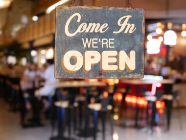 Cafe / Restaurant penceresinde 'Come in We're Open' yazan bir iş vintage işareti. Soyut bulanıklık restoran görüntüleri insanlarla. Arka plan kullanımı için müşteriile restoran
