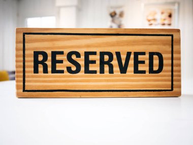 Kutlama günü konseptinde flört etmek için restoranda rezervasyon koltuğu. Kafe ile beyaz masa üzerinde ayrılmış ahşap tabelalı restoran akşam yemeği için bokeh ile ayar ve akşam ışığı süslemeleri