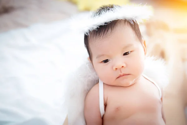 Close-up beautiful newborn baby girl. A portrait of a beautiful newborn baby girl wearing angel wings and angel ring. — Stock Photo, Image