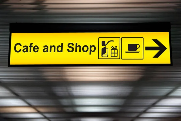 Letrero café y tienda con flecha para la dirección de los pasajeros para comprar alimentos, bebidas y compras. café amarillo y letrero de la tienda en el aeropuerto — Foto de Stock