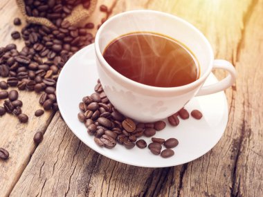 ahşap masa üzerinde kahve çekirdeği ile sıcak kahve fincanı. kafe veya kafe için kahve arka plan