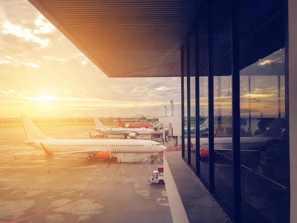 Avión en la puerta de la terminal del aeropuerto, aeropuerto internacional moderno durante la puesta del sol. transporte por avión y concepto de viaje — Foto de Stock