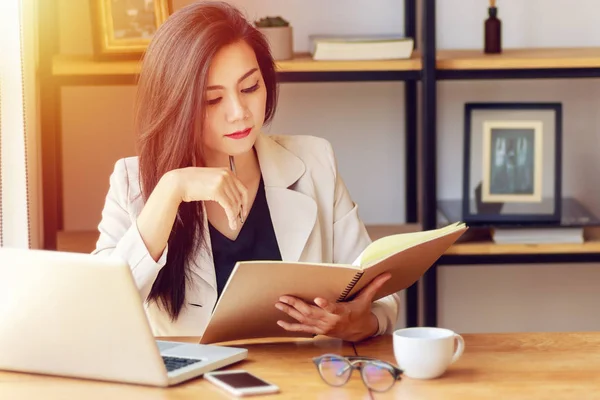 Joven mujer de negocios asiática que trabaja en el lugar de trabajo. hermosa mujer asiática en traje casual trabajando con libro de lectura, prepararse para la reunión o entrevista en la oficina moderna. freelance, start-up business en Asia —  Fotos de Stock