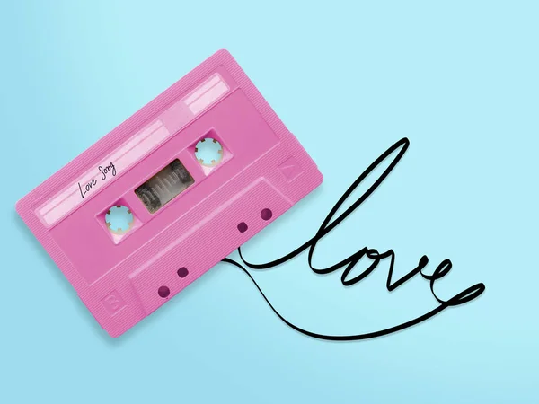 Roze audio cassette tape met label tag liefde lied verwarde tape lint woord liefde geïsoleerd op blauwe achtergrond, bovenaanzicht. — Stockfoto
