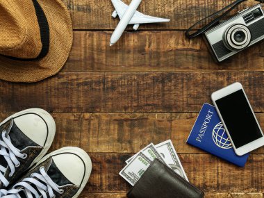 pasaport düz yatıyordu, mobil, uçak modeli, spor ayakkabı, cüzdan, kamera ve kopya alanı ile ahşap arka plan üzerinde seyahat aksesuarları öğeleri. seyahat ve tatil konsepti