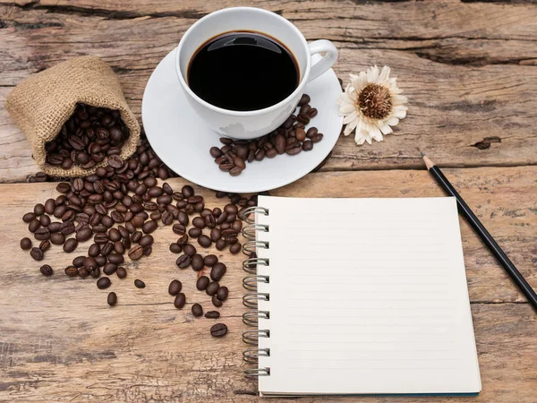 Чашка горячего кофе с кофейными зернами и блокнот на деревянном столе. Кофе фоновое меню для кафе или кафе, рецепт для бариста . — стоковое фото