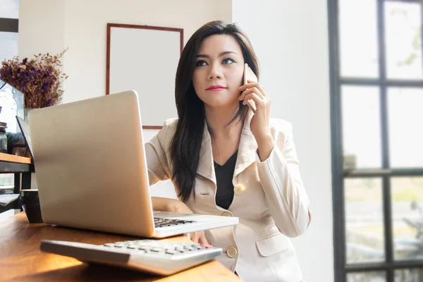Asian business woman working with laptop notebook and use mobile smartphone for contact communication with colleagues. implementation and coordination by using modern technology