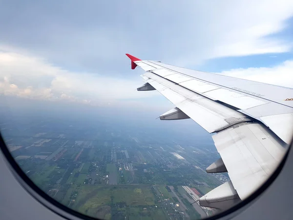 Θέα στην πόλη σύννεφα και τον ουρανό όπως φαίνεται μέσα από το παράθυρο ενός αεροσκάφους. ιδέα για ταξίδια και διακοπές — Φωτογραφία Αρχείου