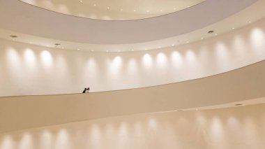 Sahne ışıkları ve yürüyen insanlarla beyaz duvarlı beyaz sarmal merdivenler.