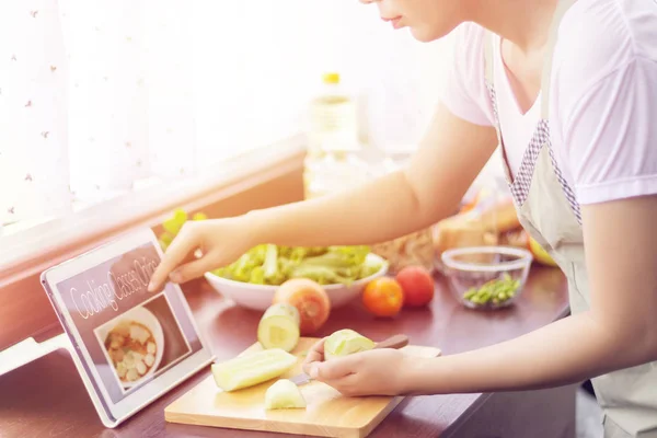 Asyalı kadın tablet üzerinden web sitesinde pişirme sınıfı online ders takip pişirme için malzemeler hazırlamak. modern yaşam tarzı kavramı için internet teknolojisi pişirme içeriği — Stok fotoğraf