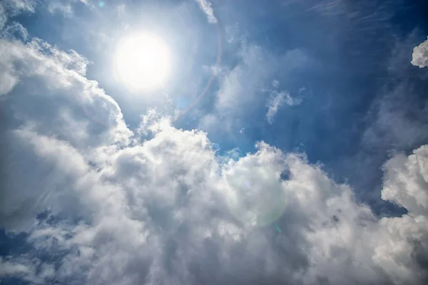 Fundo ensolarado, céu azul com nuvens brancas e clarão de luz solar — Fotografia de Stock