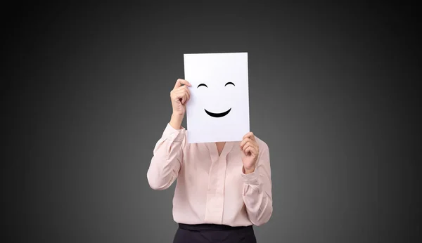 Empresária segurando um cartão com desenho expressões faciais ilustrações sentimentos emoção rosto no white paper — Fotografia de Stock