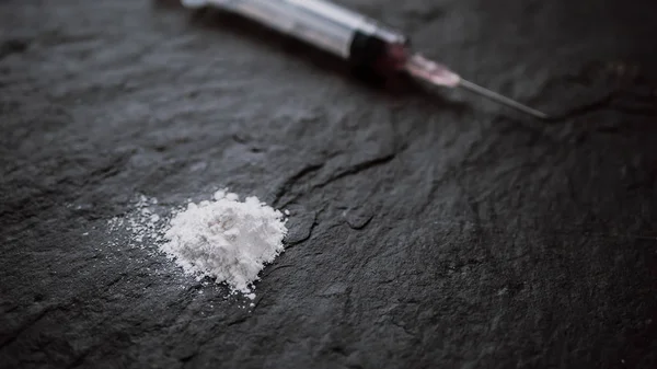 Drugsverslaafde concept. Close-up van medicijn spuit en gekookte heroïne op zwarte achtergrond — Stockfoto