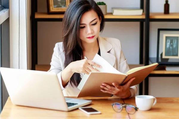 Joven mujer de negocios asiática que trabaja en el lugar de trabajo. hermosa mujer asiática en traje casual trabajando con libro de lectura, prepararse para la reunión o entrevista en la oficina moderna. freelance, start-up business en Asia —  Fotos de Stock