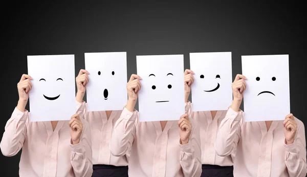 Fem affärskvinna innehar ett kort med ritning ansiktsuttryck olika känslor känslor ansikte på vitt papper — Stockfoto