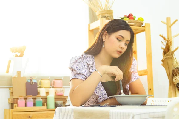 Mujer asiática solitaria sentarse a la mesa comiendo comida en la cocina solo en la mañana con hermosa luz del sol con espacio de copia — Foto de Stock