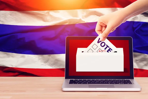 Online-Abstimmung, Umfrage, Exit Polls für das thailändische Wahlkonzept. Nahaufnahme einer Person, die einen Stimmzettel bei Wahlen während der Stimmabgabe auf Leinwand im Hintergrund der thailändischen Flagge abgibt. — Stockfoto