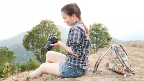 若いアクティブなアジアの観光客の女性の旅行写真家は デジタルカメラで写真を撮るバックパックを持つ山の自然のビューの視点で 撮影した後 画面上の画像を確認し — ストック動画
