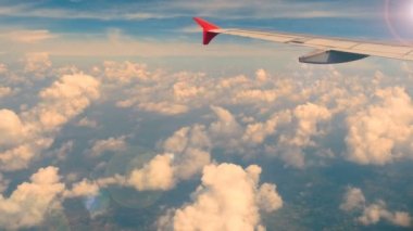 4k görüntü. hava yoluyla seyahat. uçak penceresinden havadan görünüm. arka plan için mavi gökyüzünde lens parlama ve güzel beyaz bulutlar ile gün batımı veya gündoğumu saatinde kanat uçak