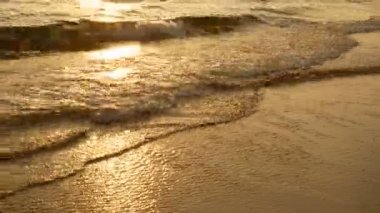 tropikal plajda 4k inanılmaz gün batımı. gün batımı sırasında sahilde okyanus plaj dalgaları, güneş ışığı su yüzeyine yansıtmaktadır. akşam doğa güzel deniz arka plan.
