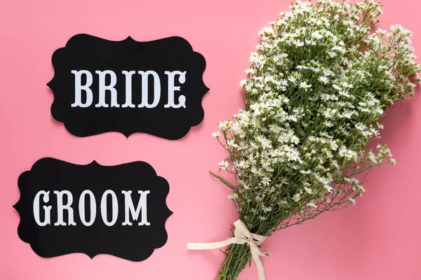 Sinal de texto de noiva e noivo no fundo rosa decorado com buquê de flores brancas, estilo vintage. conceito de sinal de casamento — Fotografia de Stock