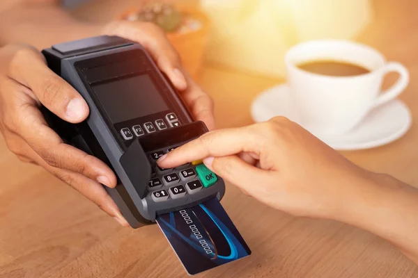 close up of hand entering credit card pin code for security password in credit card swipe machine at point of sale terminal in shop during shopping time