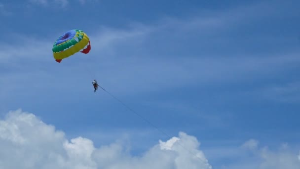 4K滑翔伞活动 五颜六色的滑翔伞翼飞行与游客在蓝天多云的天空 极限运动 夏季活动在海滩上 — 图库视频影像